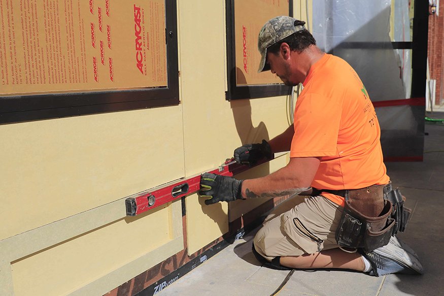 Leveling fiber-cement trim panel on façade.