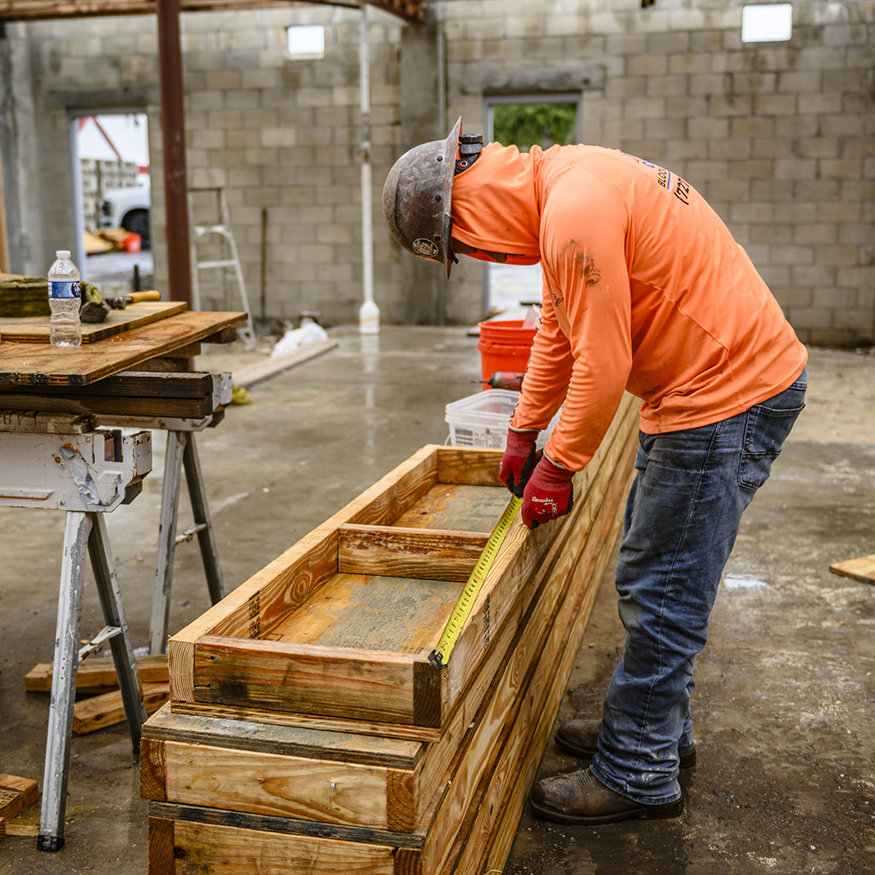 Workers assemble lumber and plywood for foundation forms.