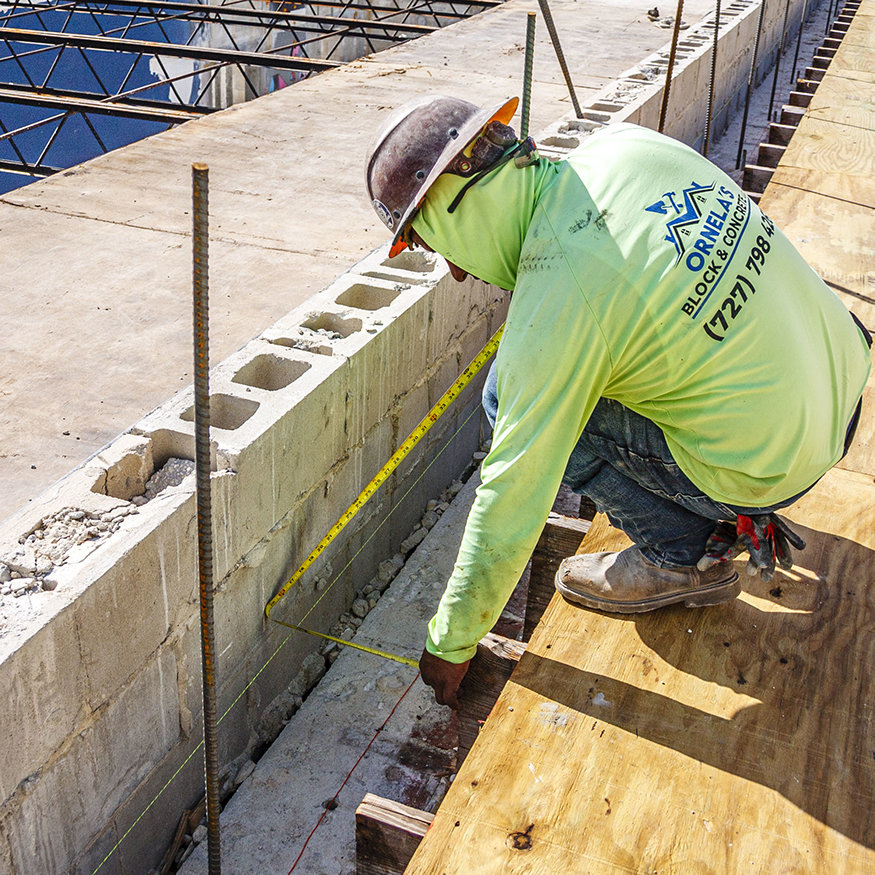Worker measures parapet wall layout.