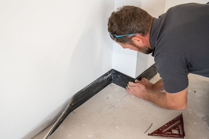 Securing baseboards along wall.