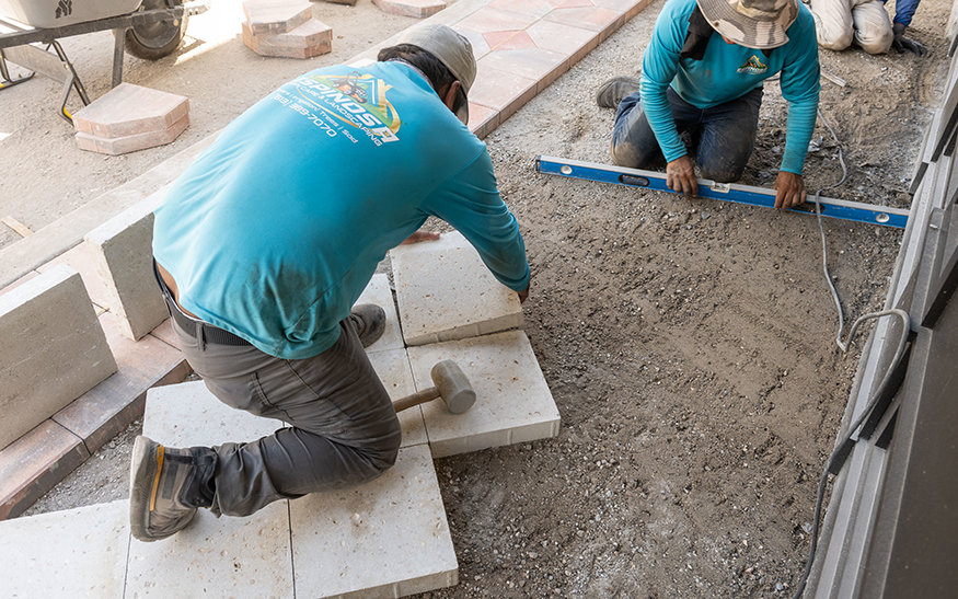 Crew levels sidewalk pavers.