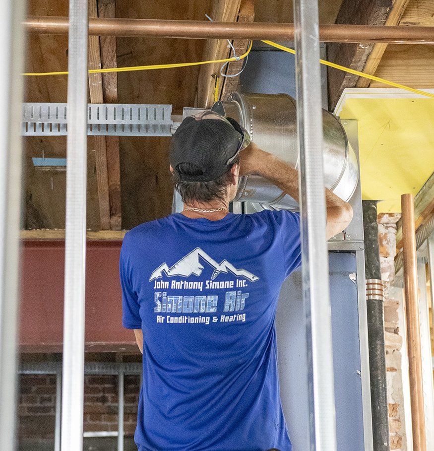 Worker aligning ductwork sections.