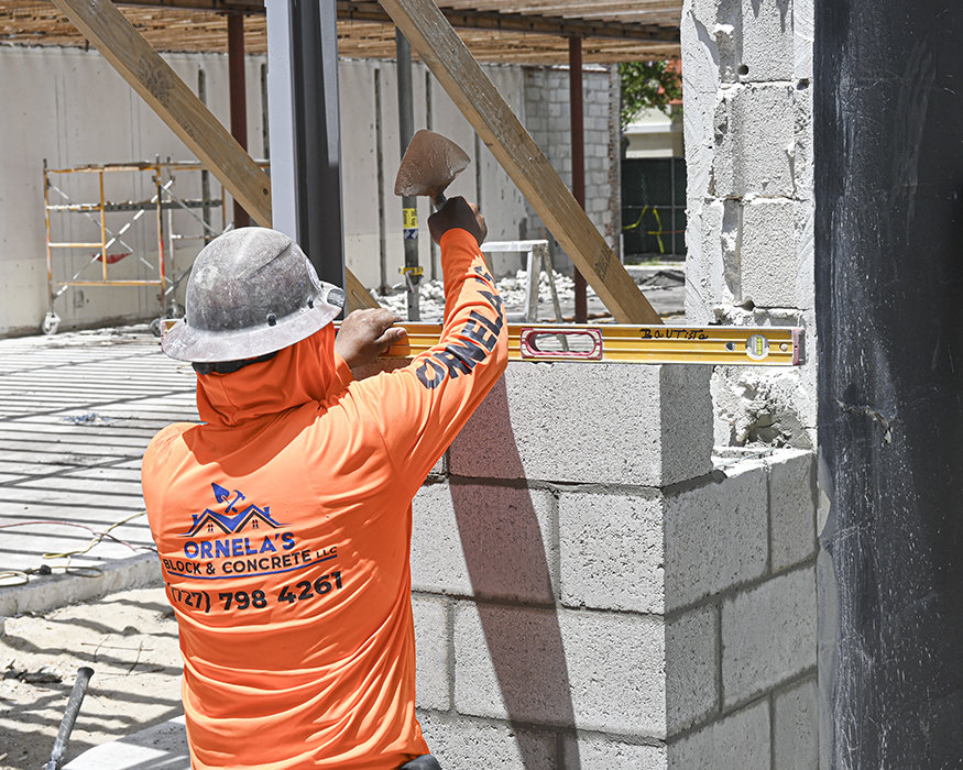 Mason levels concrete blocks during wall reconstruction.