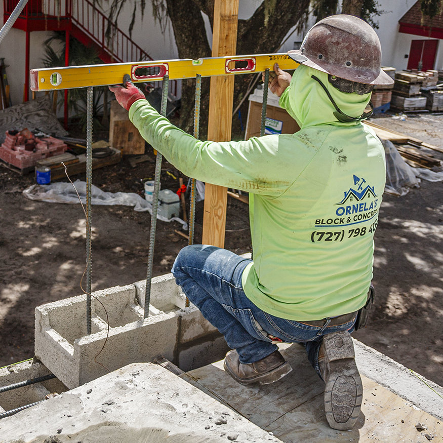 Worker verifies masonry alignment with level.