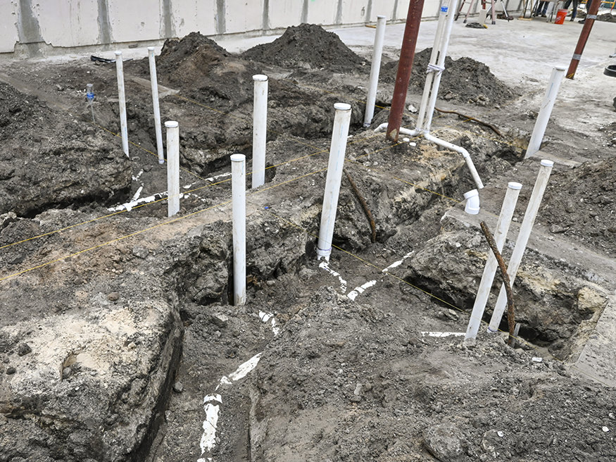 PVC plumbing pipes and fixture stub-ups in trenches.