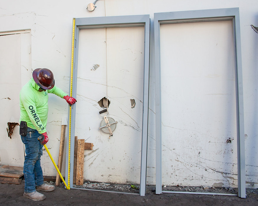 Worker measures height of new wall opening.