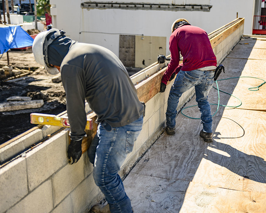 Worker checks parapet formwork with level.