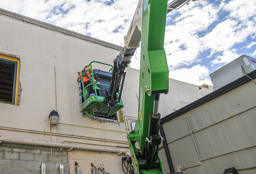 A lift is used to access upper window openings during bracket installation.